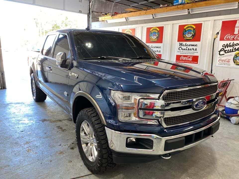 A blue ford f150 truck is parked in a garage.