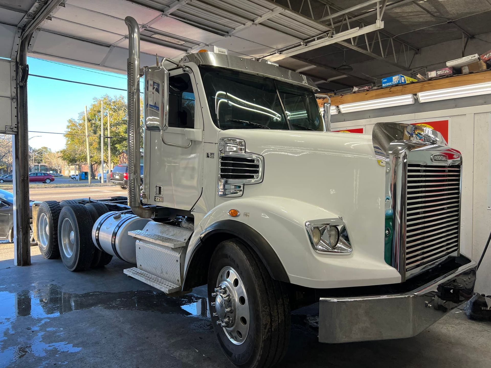 A white semi truck is parked in a garage.
