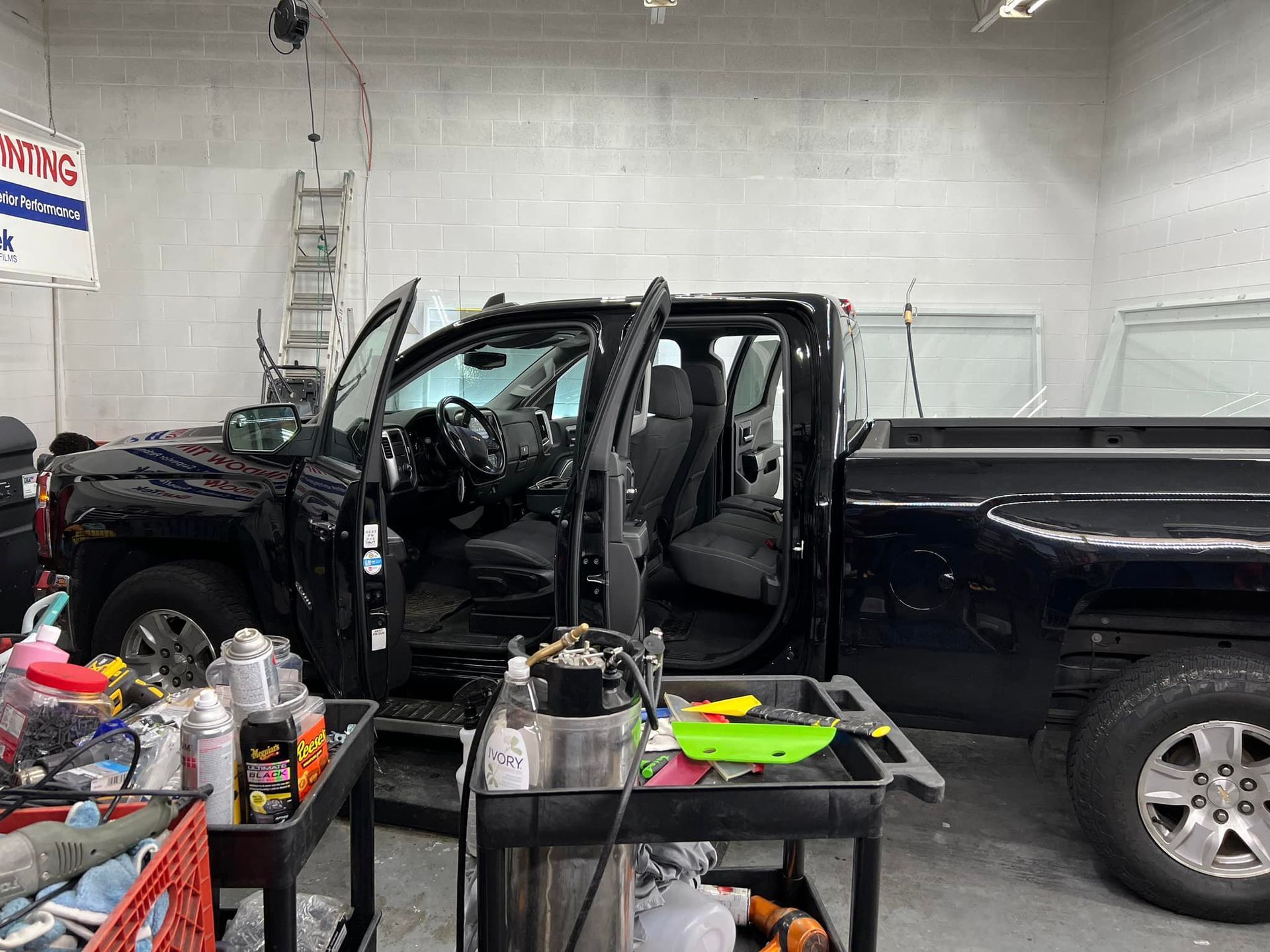 A black truck is parked in a garage with its doors open.