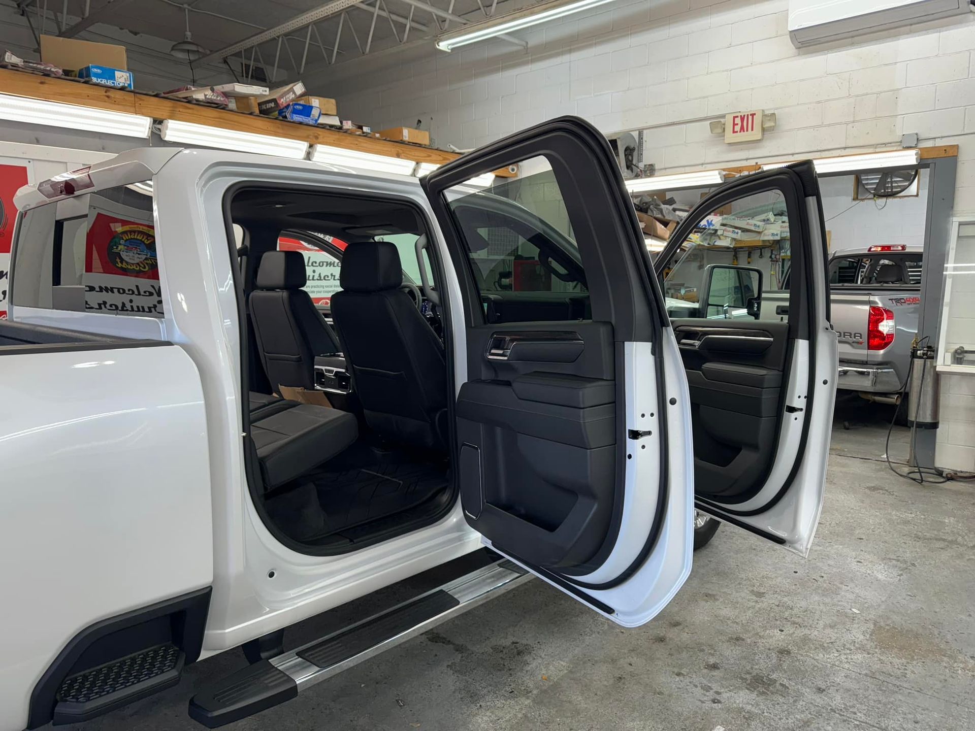 A white truck is parked in a garage with its doors open.