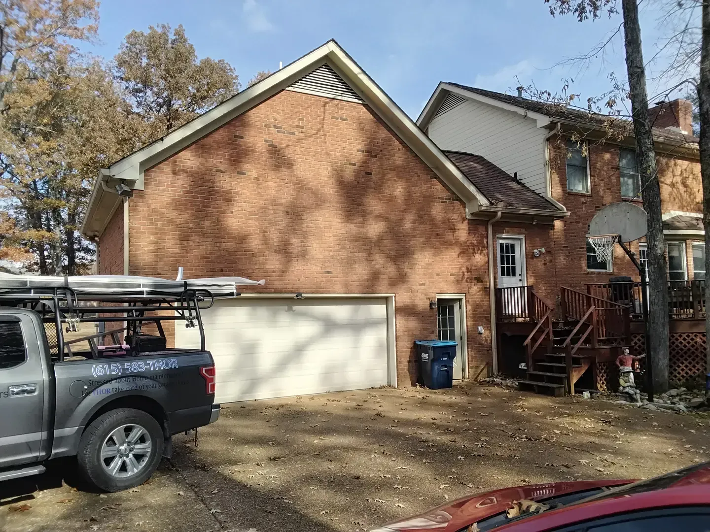 Brick house with attached garage, back deck, and parked pickup truck in a driveway.