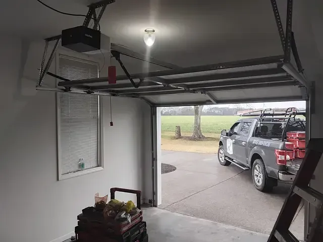 Garage interior with open door, a truck parked outside, and a garage door opener.