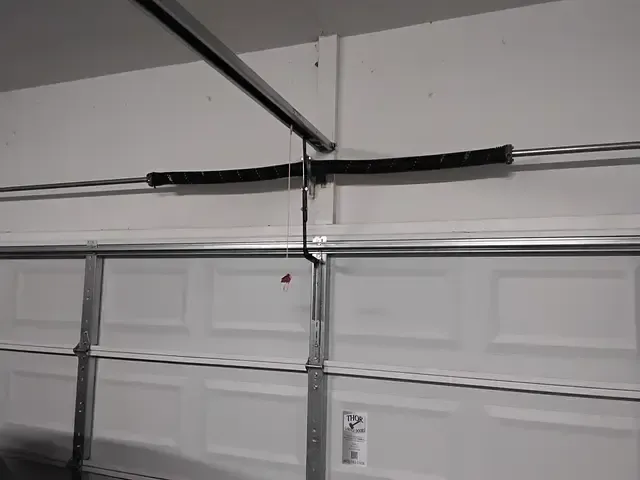 White garage door with overhead torsion spring system.