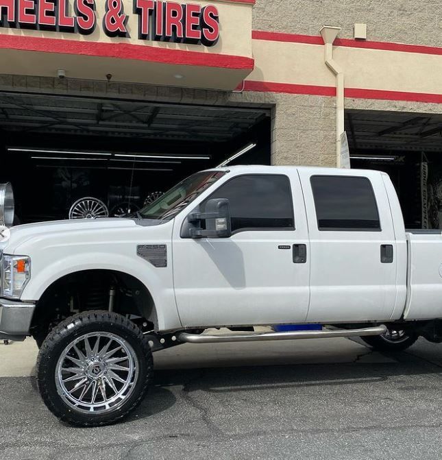 A white truck is parked in front of A J Wheels & Tires