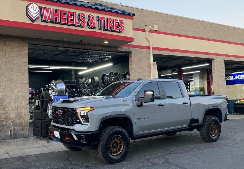 A gray truck is parked in front of A J Wheels & Tires