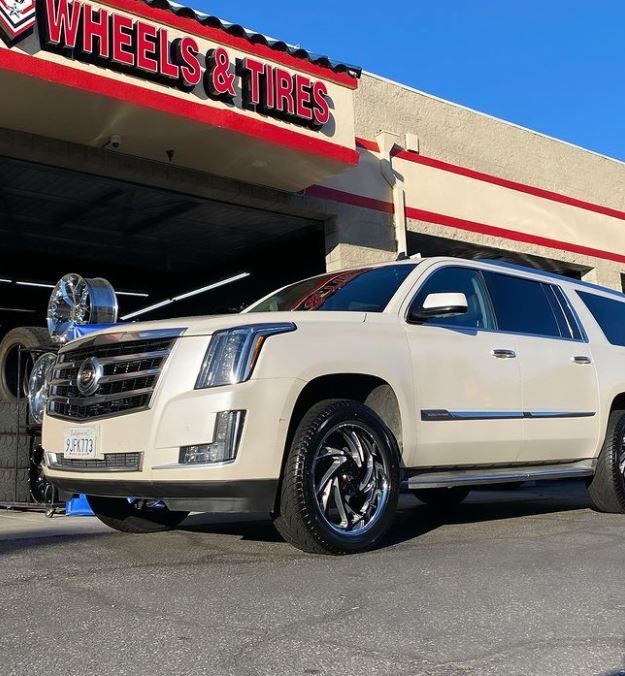 A white SUV is parked in front of A J Wheels & Tires