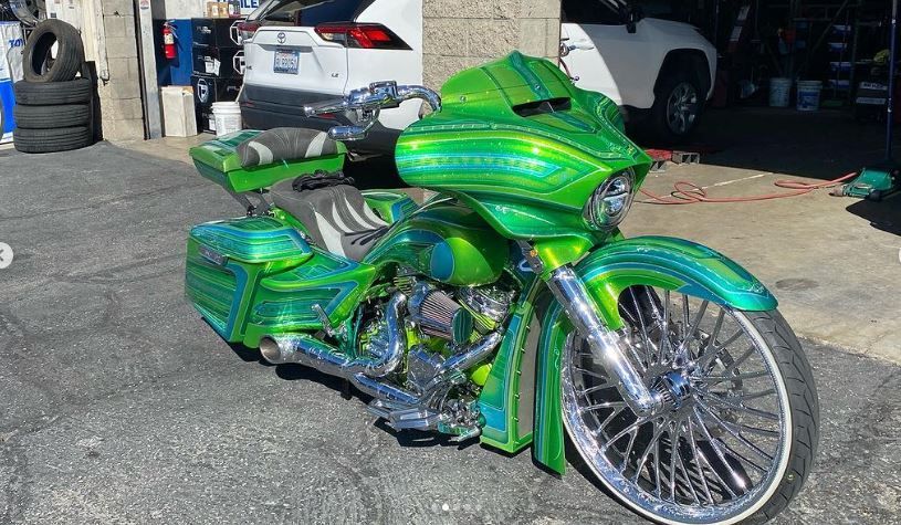A green and blue motorcycle is parked in front of a shop