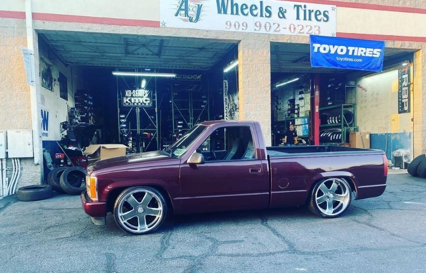 A purple truck is parked in front of A J Wheels & Tires