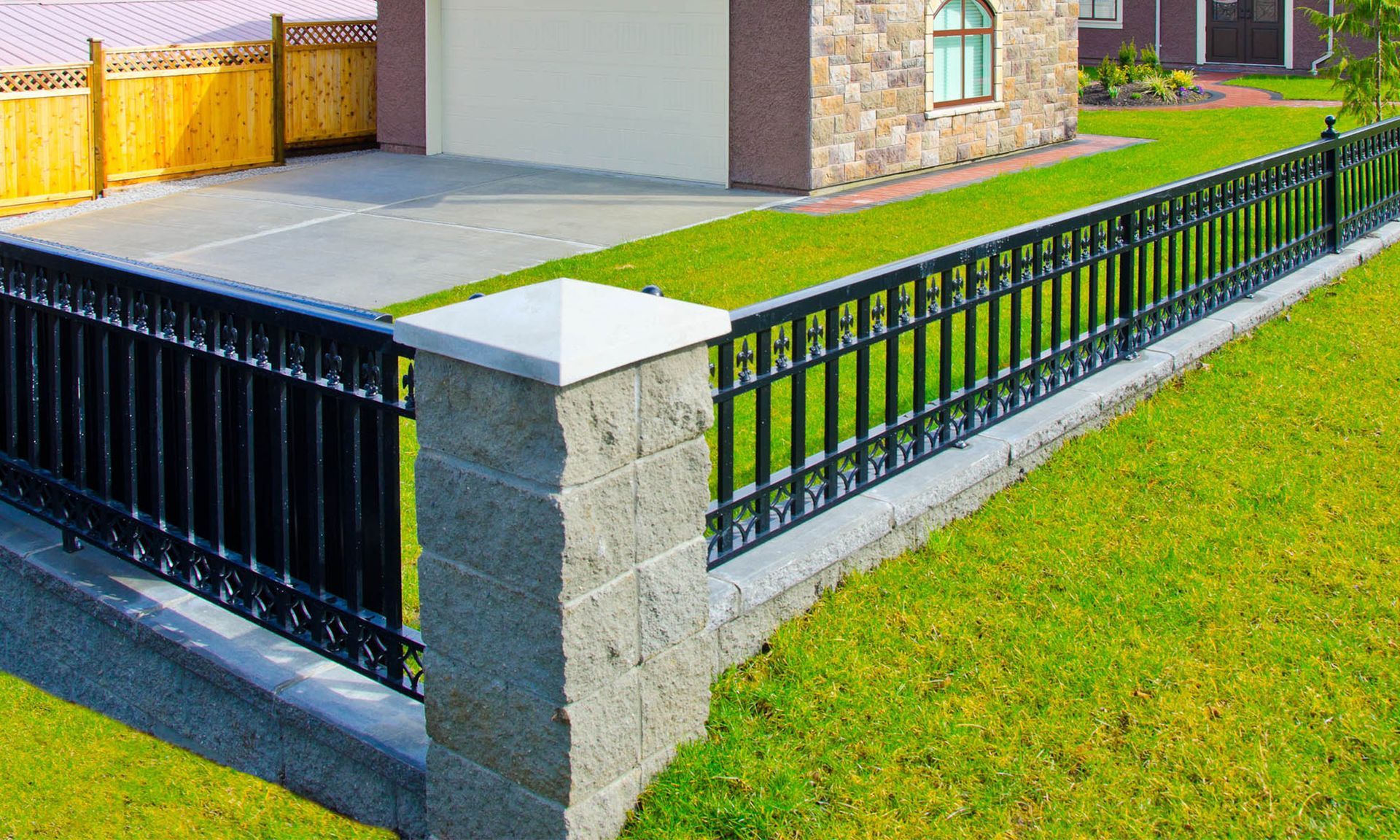 a black fence surrounds a brick wall in front of a house .