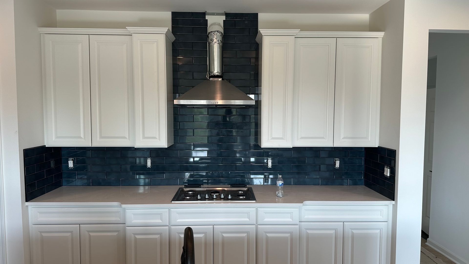 A kitchen with white cabinets and a stove top oven