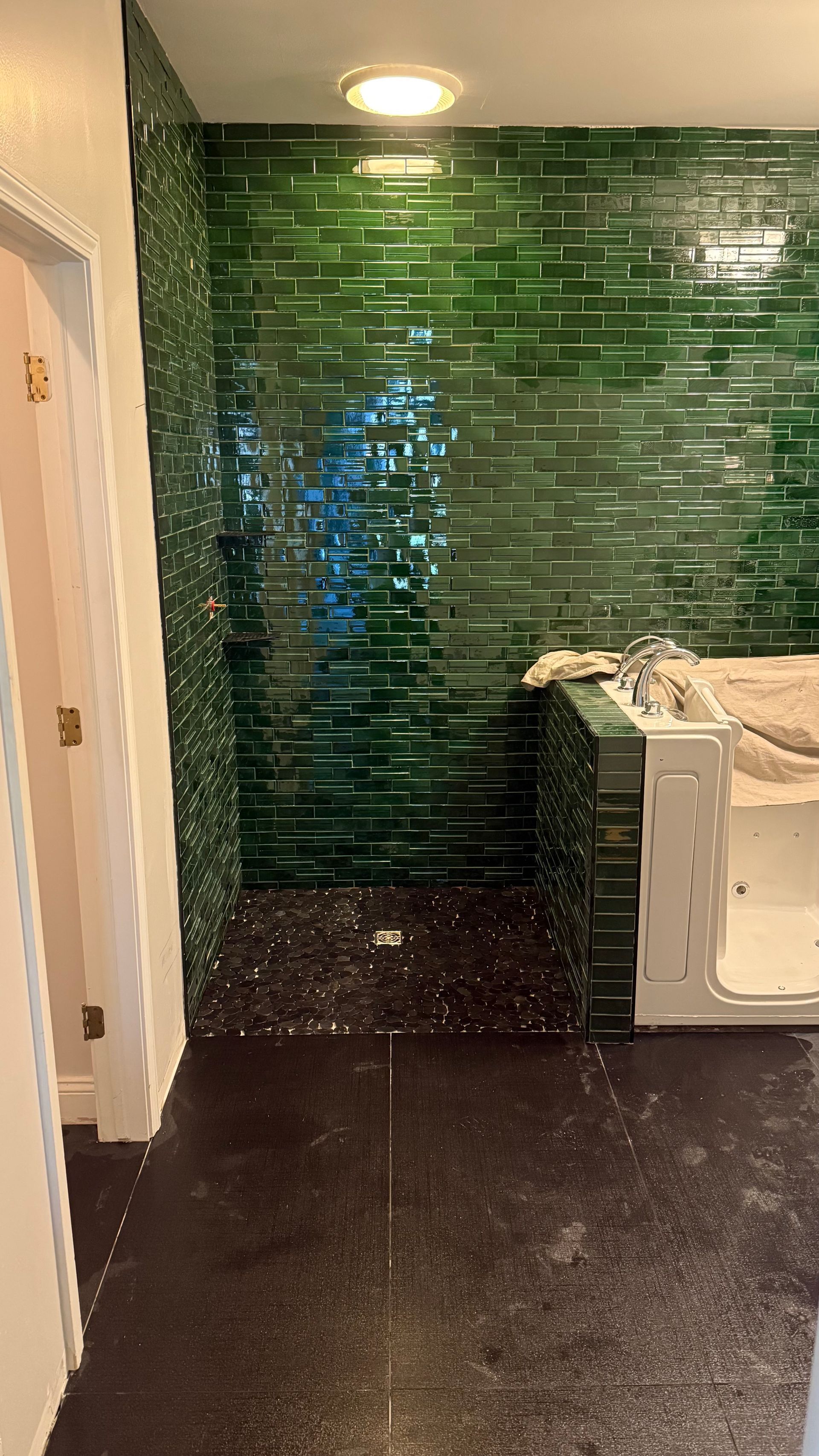 A bathroom with green tiles and a walk in shower.