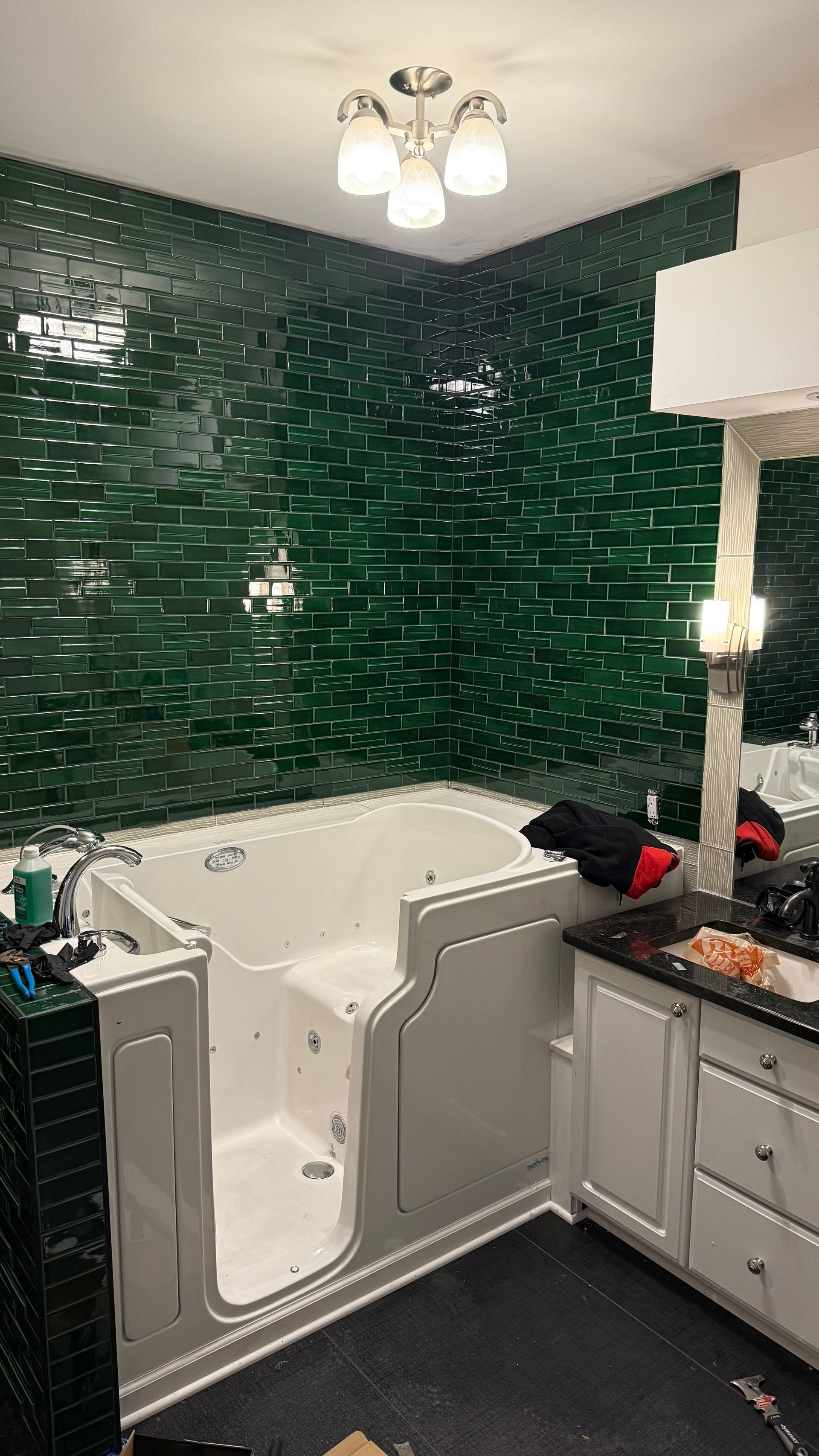 A bathroom with green tiles and a walk in tub.