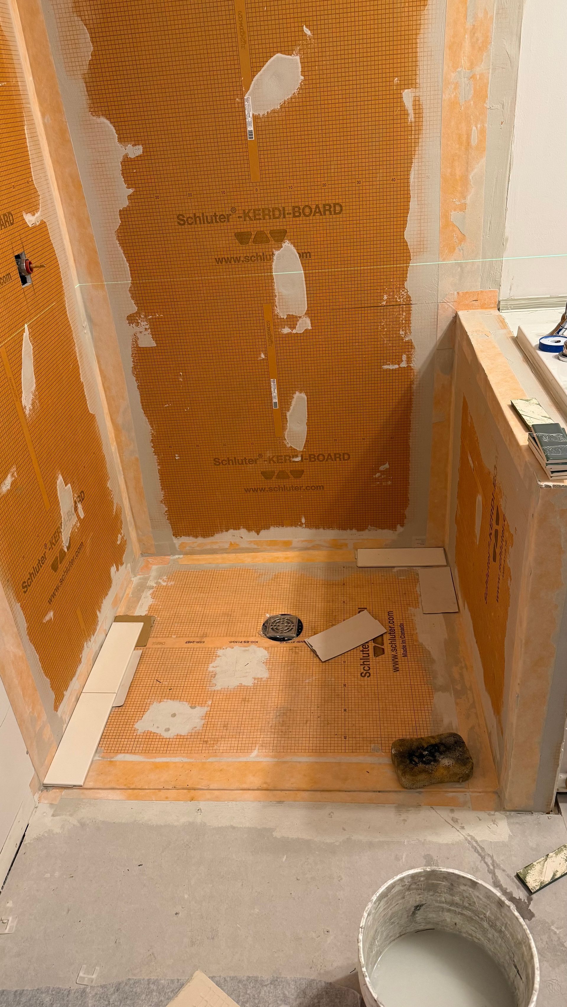 A bathroom under construction with a bucket of paint on the floor.
