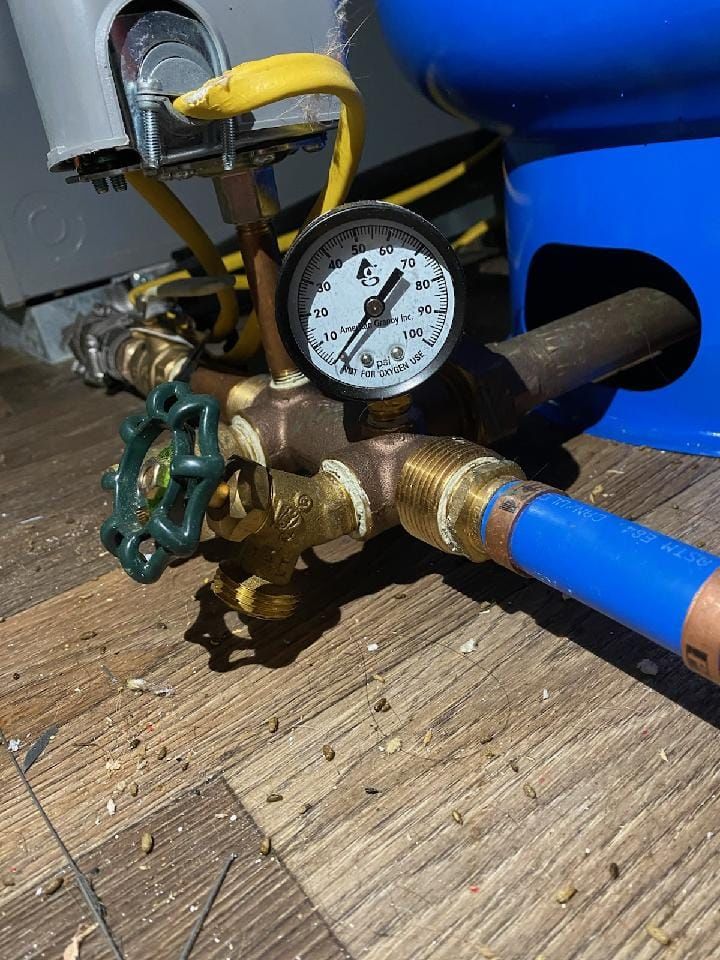 a pressure gauge is sitting on top of a wooden floor next to a blue pipe