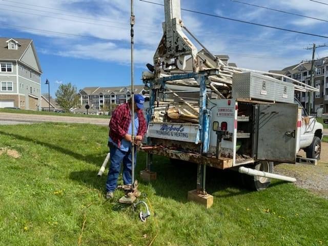 a man is digging a hole in the grass in front of a truck