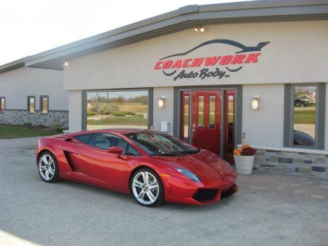 Red Lamborghini sports car parked in front of the Coachwork Auto Body INC. building.