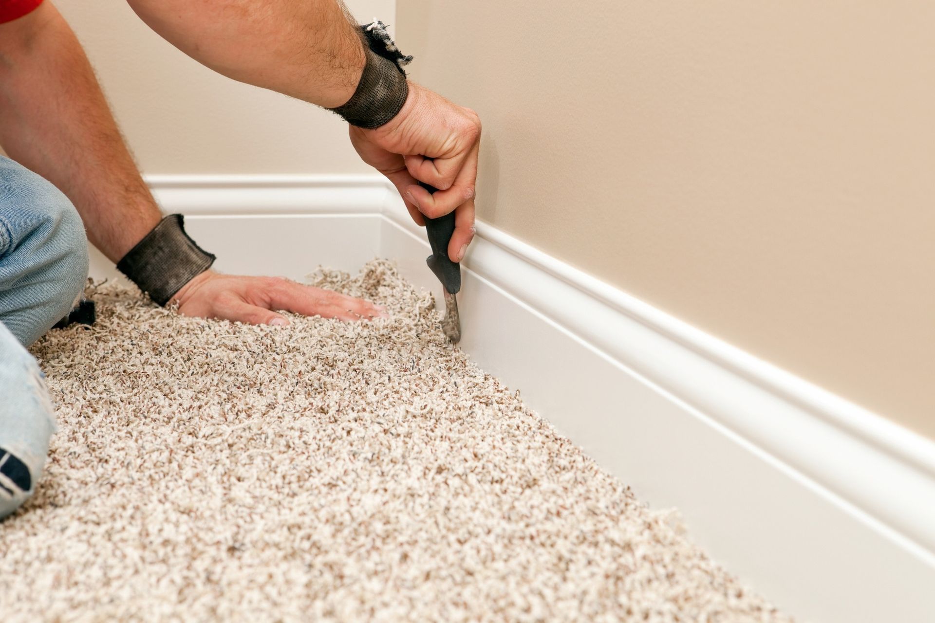 A man is laying carpet on the floor in a room.