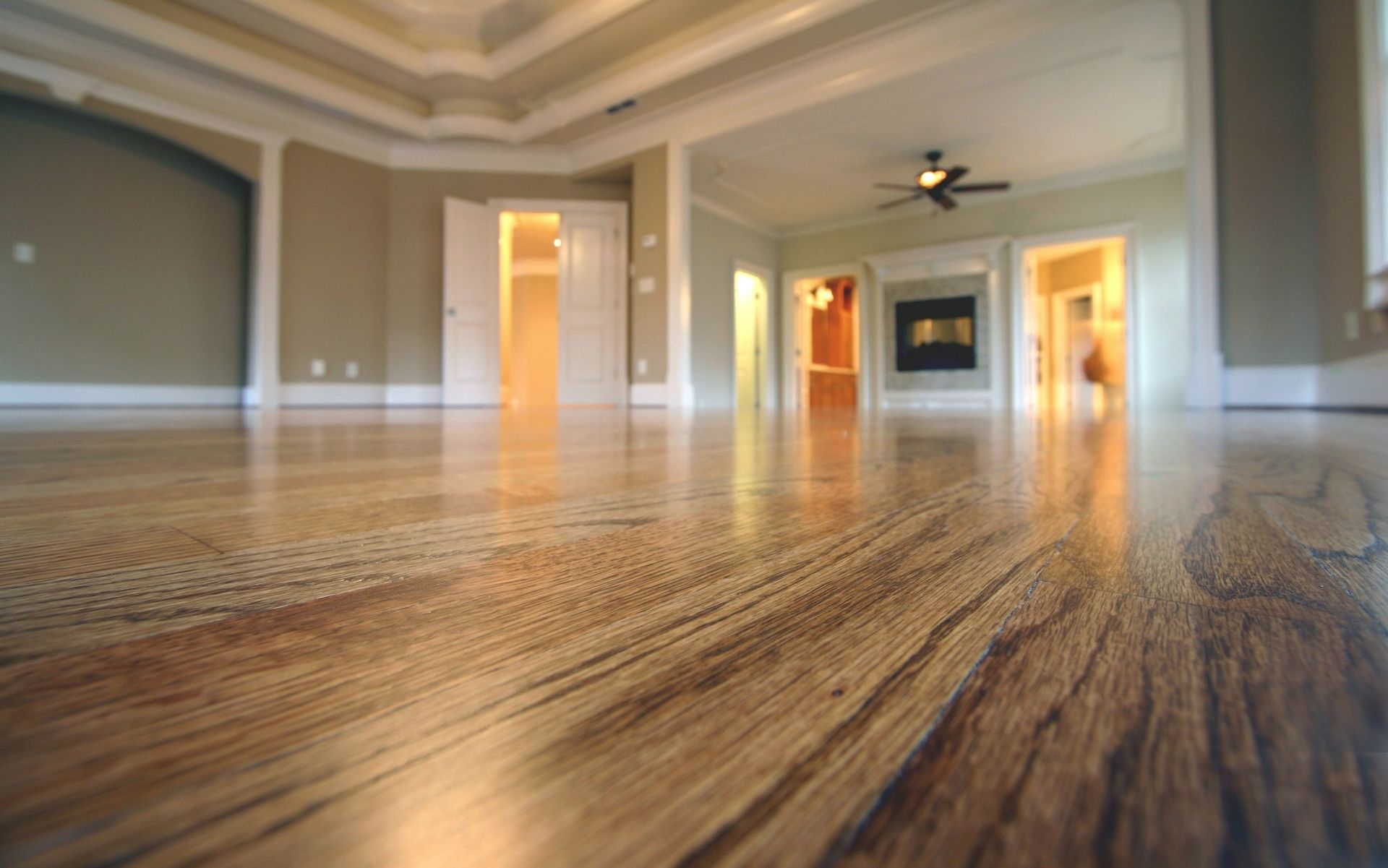 A large empty room with hardwood floors and a ceiling fan.