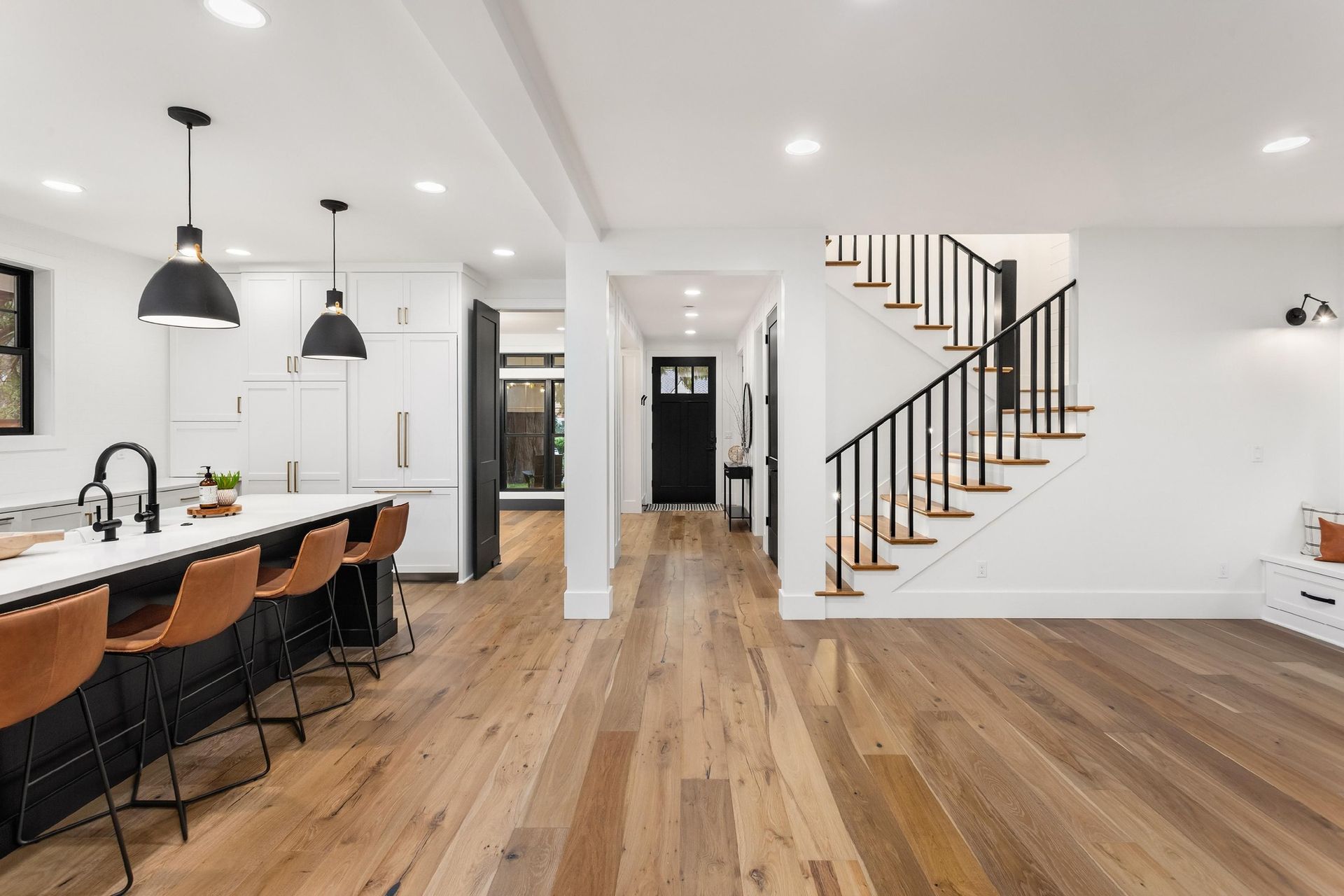 A kitchen with hardwood floors and a staircase leading to the second floor.