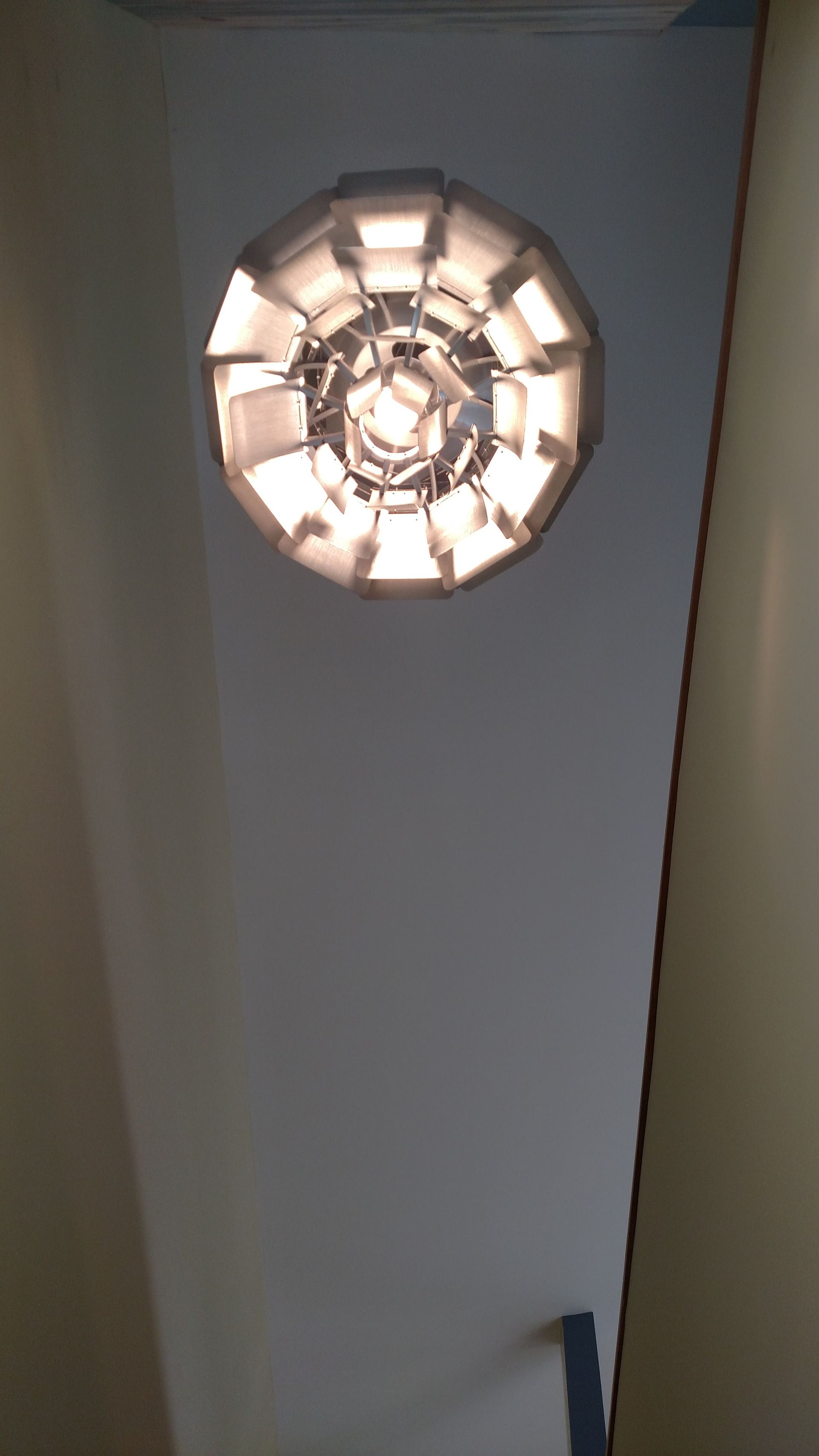 Circular light fixture hanging from a white ceiling.