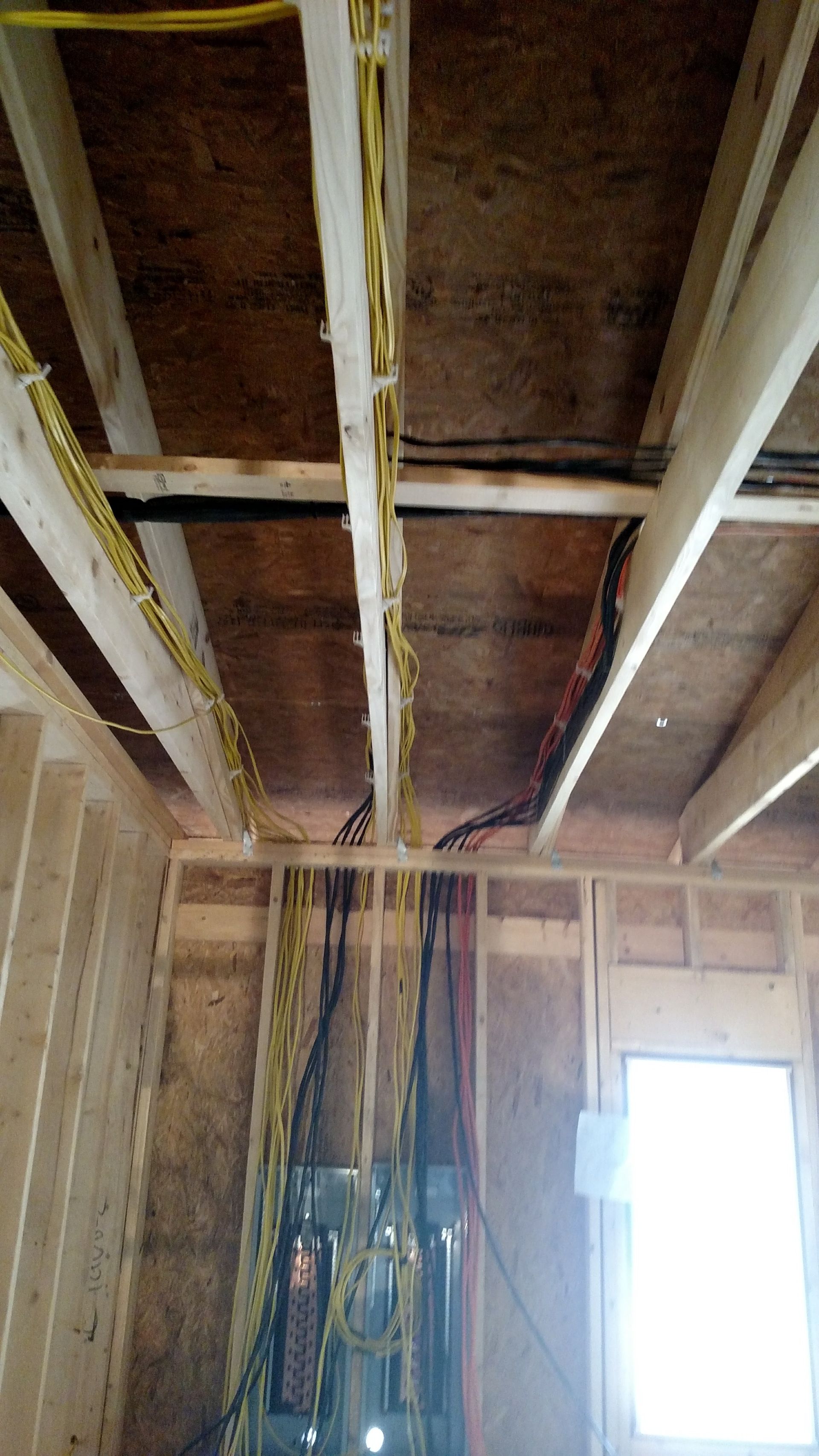 Interior view of exposed wooden ceiling beams with electrical wiring.