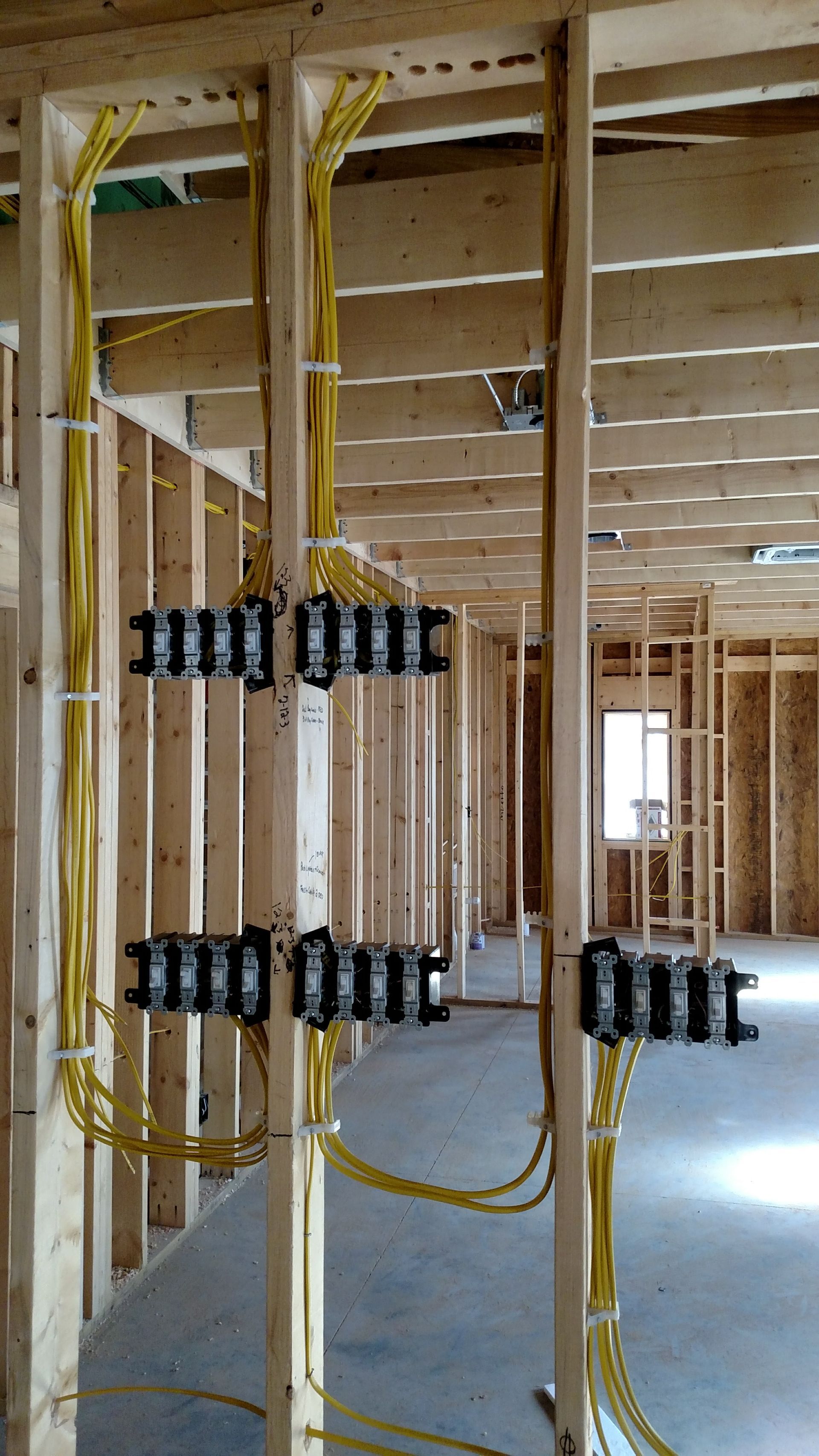 Electrical wiring and junction boxes installed in the wooden framing of a building under construction.