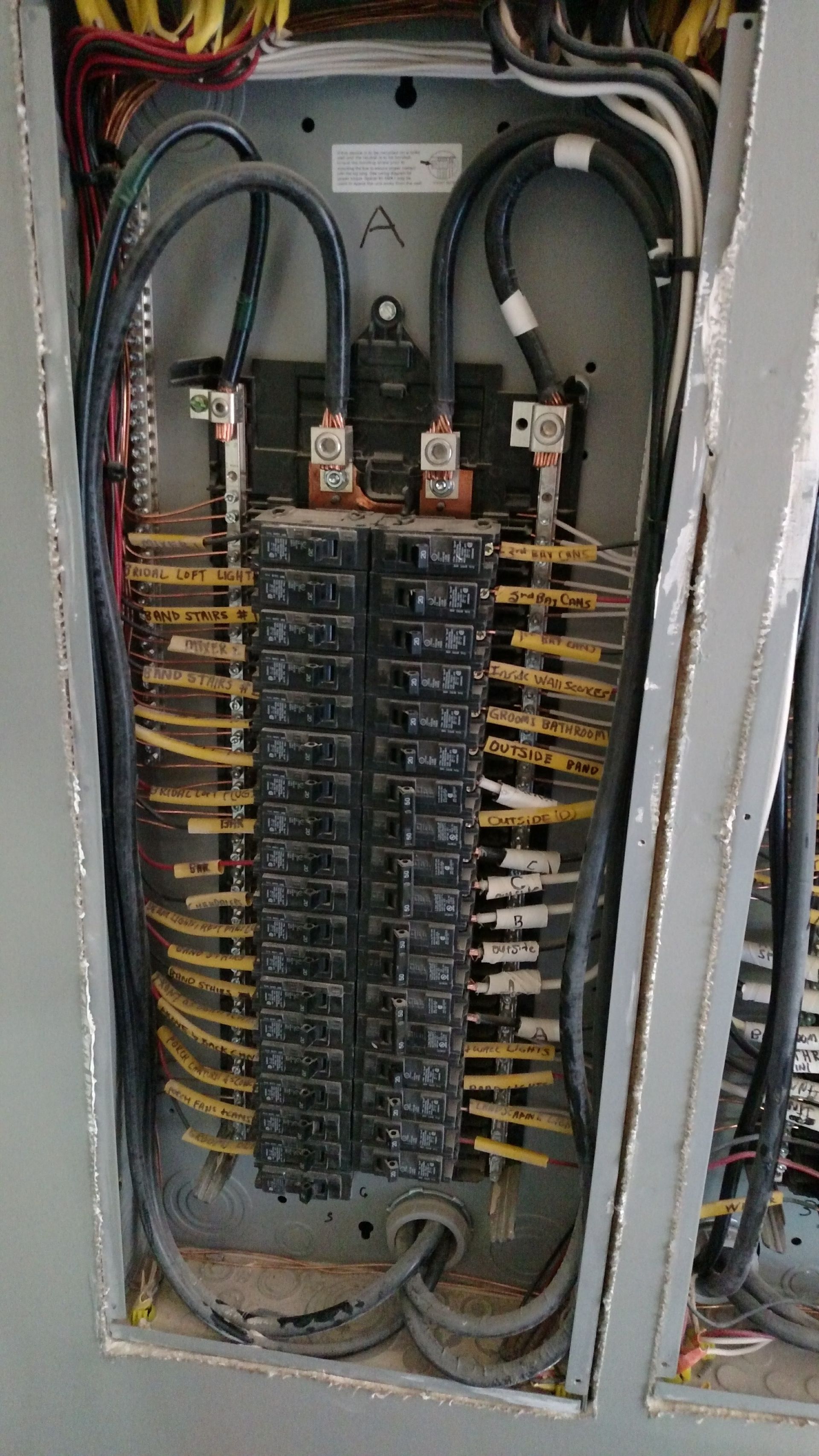 Electrical panel with numerous black circuit breakers and wiring.
