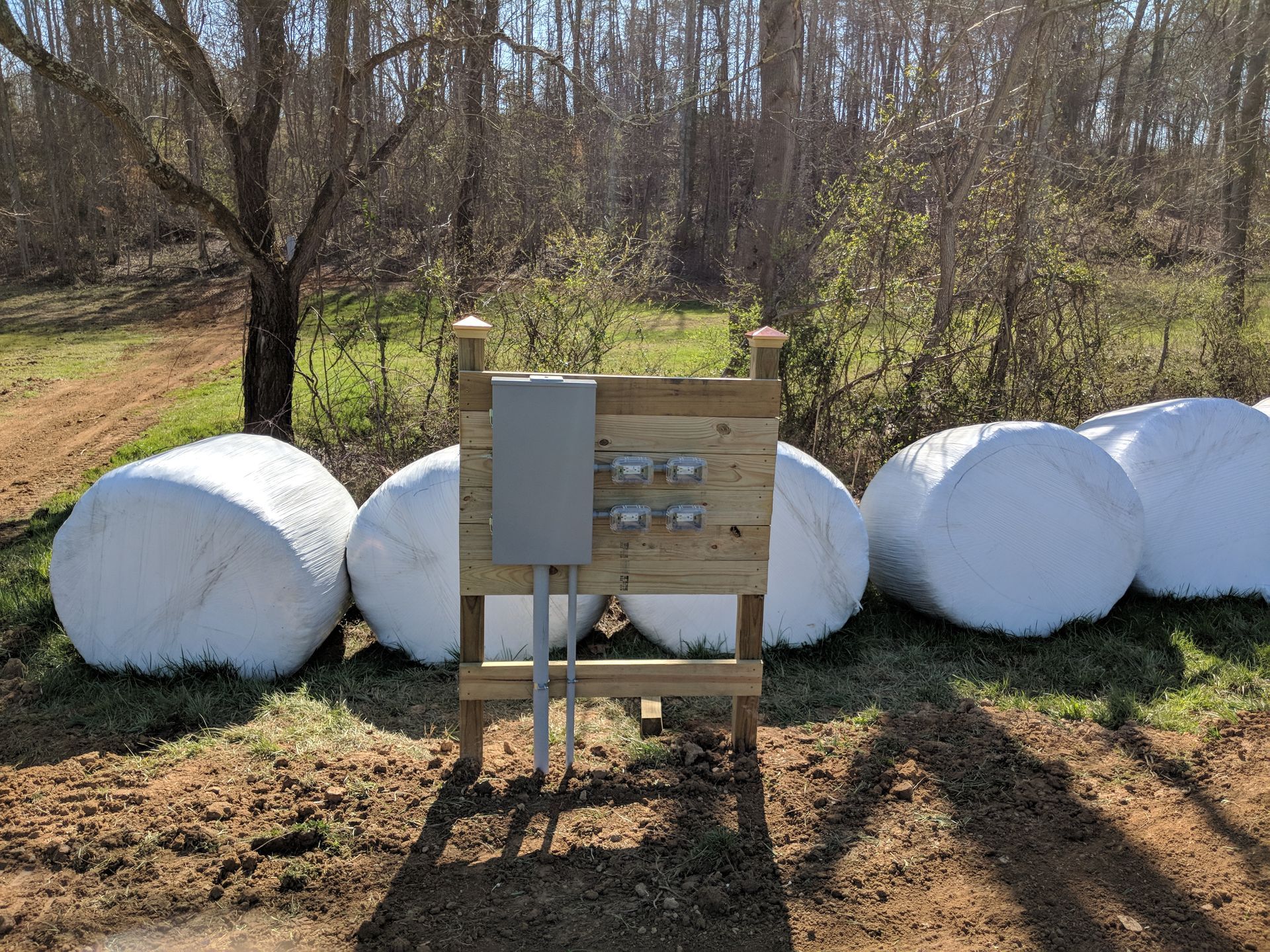 Electrical box mounted on wooden frame, set amongst hay bales.