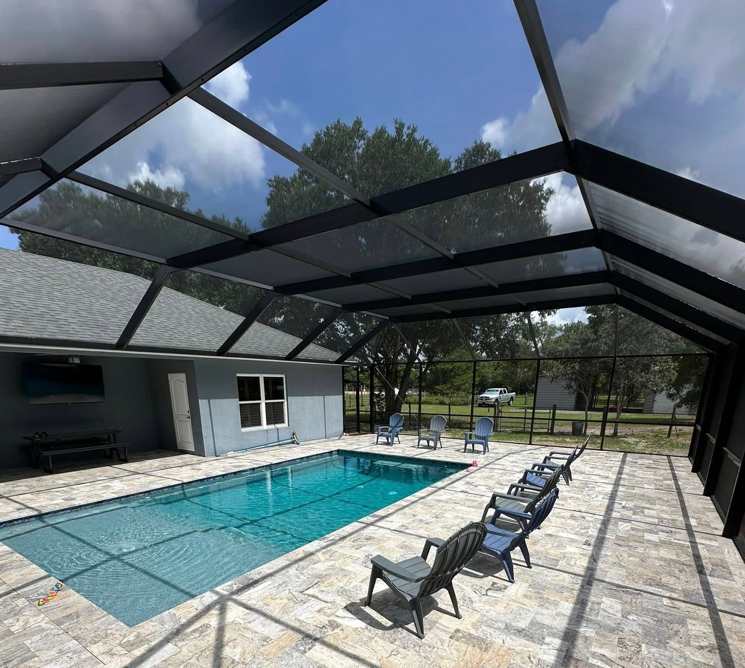 Screened-in patio with a turquoise pool and lounge chairs in bright sunlight
