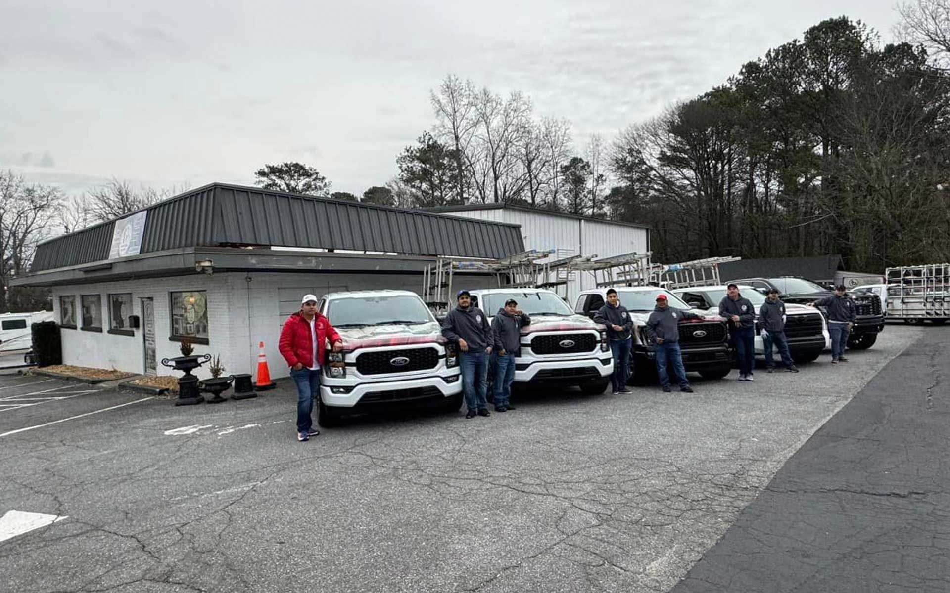 A group of men are standing in front of a row of trucks.