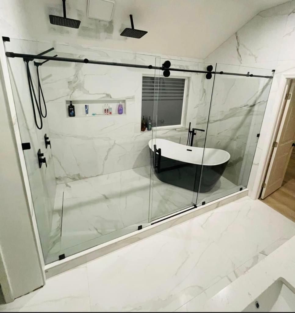 A bathroom with a bathtub and a shower with a sliding glass door.