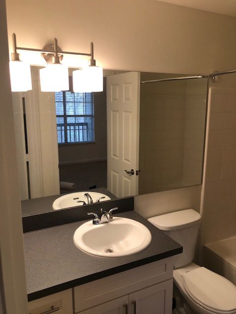A bathroom with a sink toilet and mirror