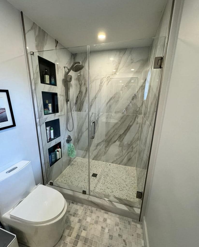 A bathroom with a toilet and a walk in shower with a glass door.