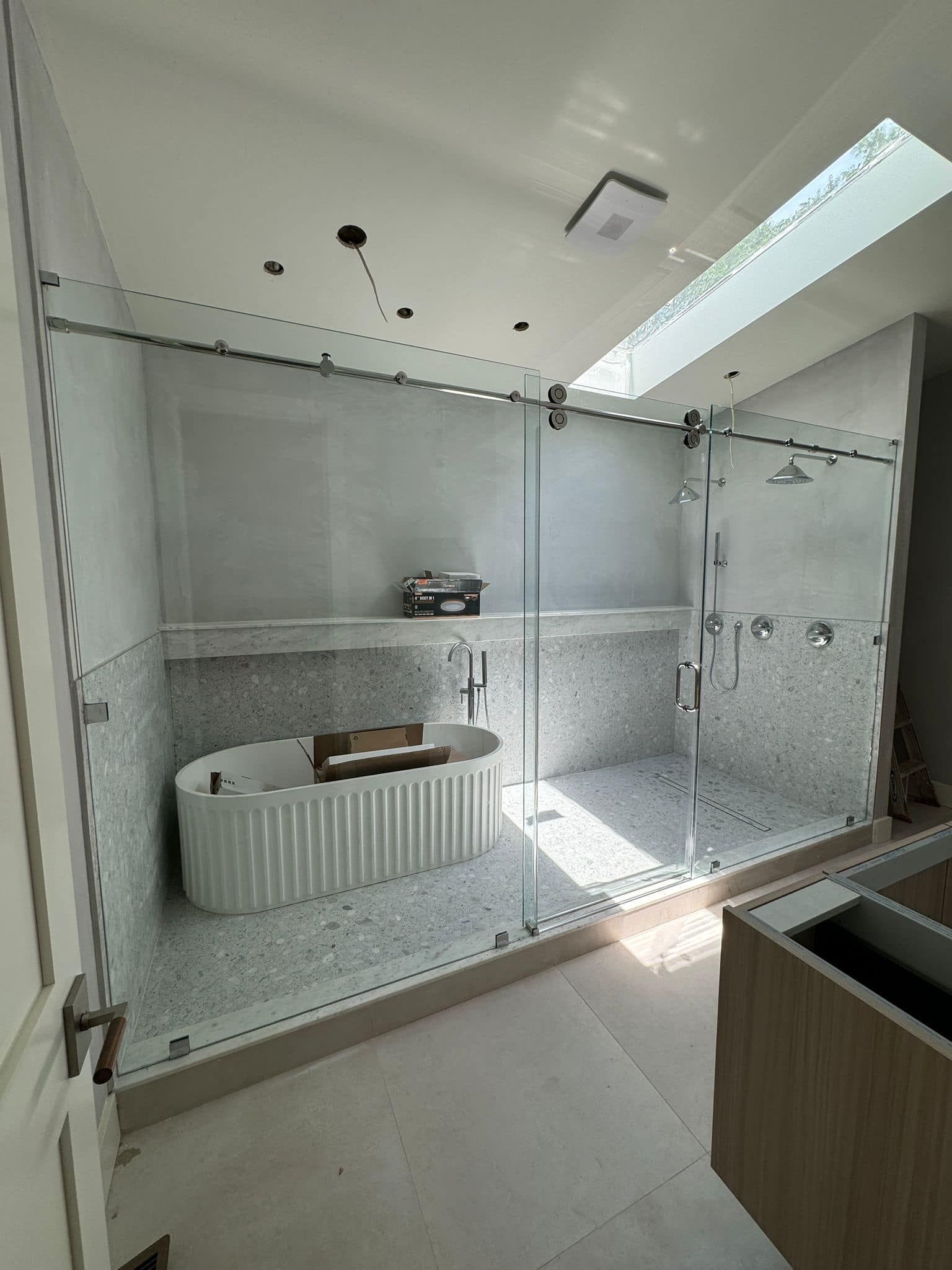 A bathroom with a bathtub , shower , and skylight.