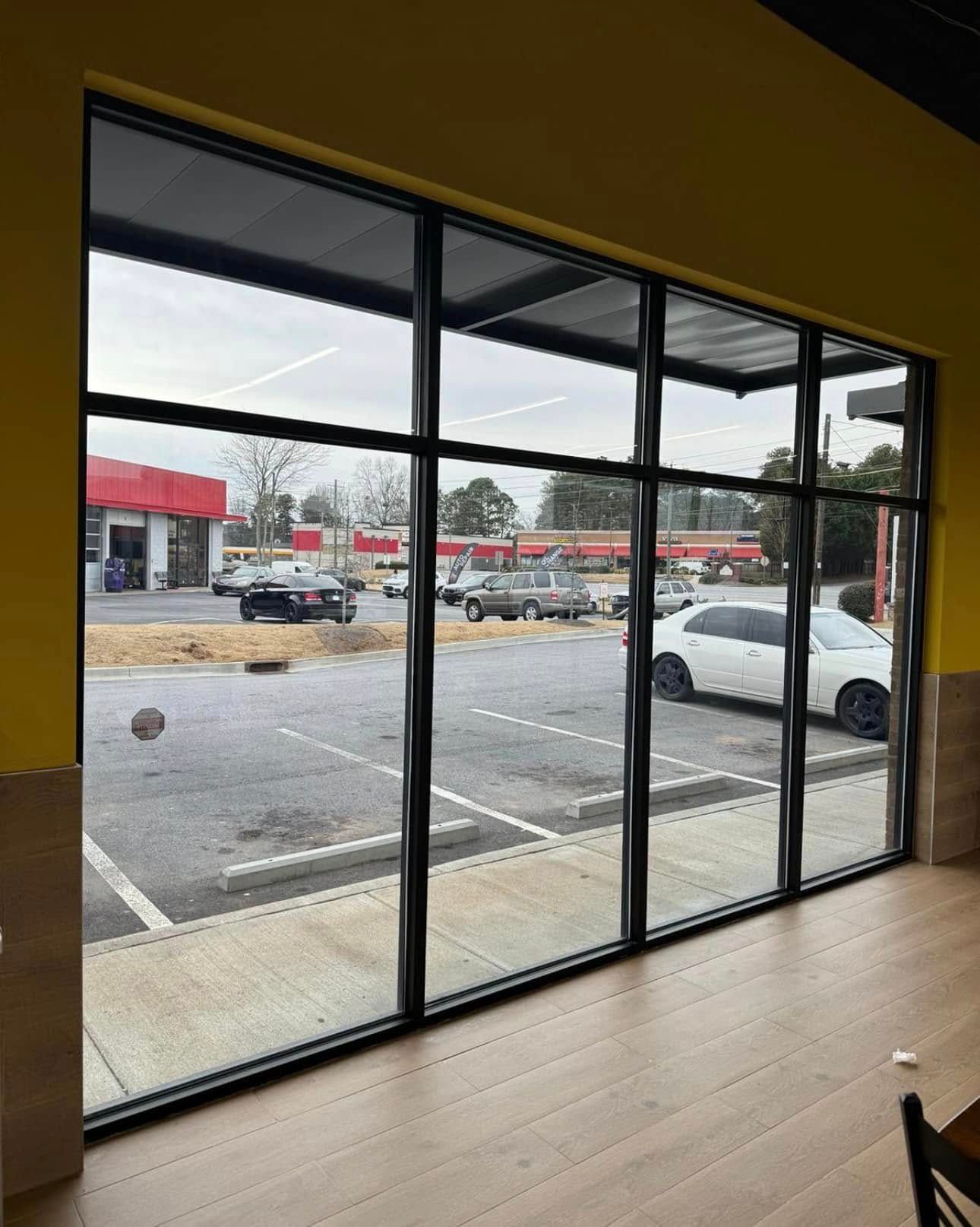 A restaurant with a lot of windows and a parking lot in the background.
