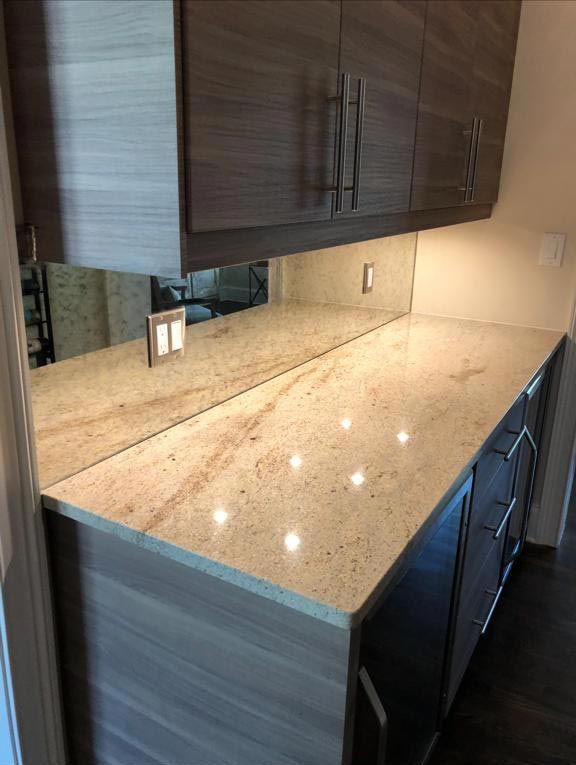 A kitchen with a granite counter top and a large mirror.