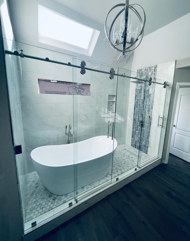 A bathroom with a sliding glass shower door and a bathtub.