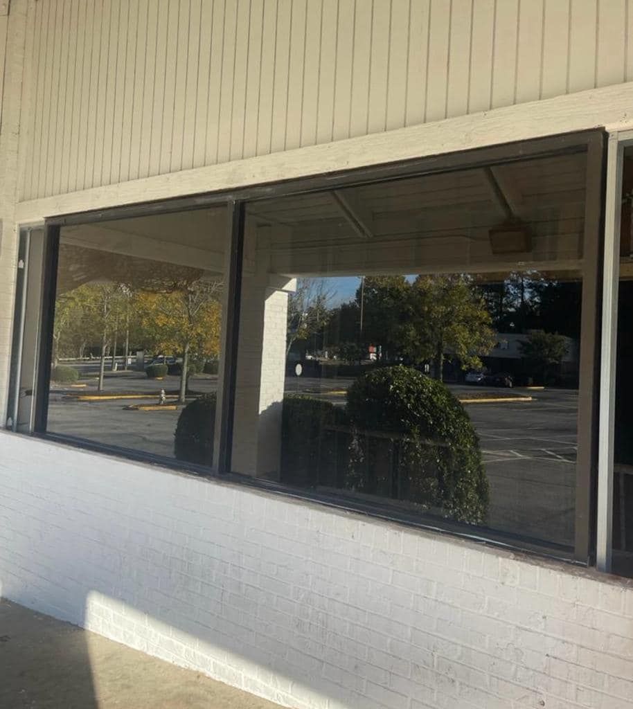 A large window on the side of a building with trees reflected in it.