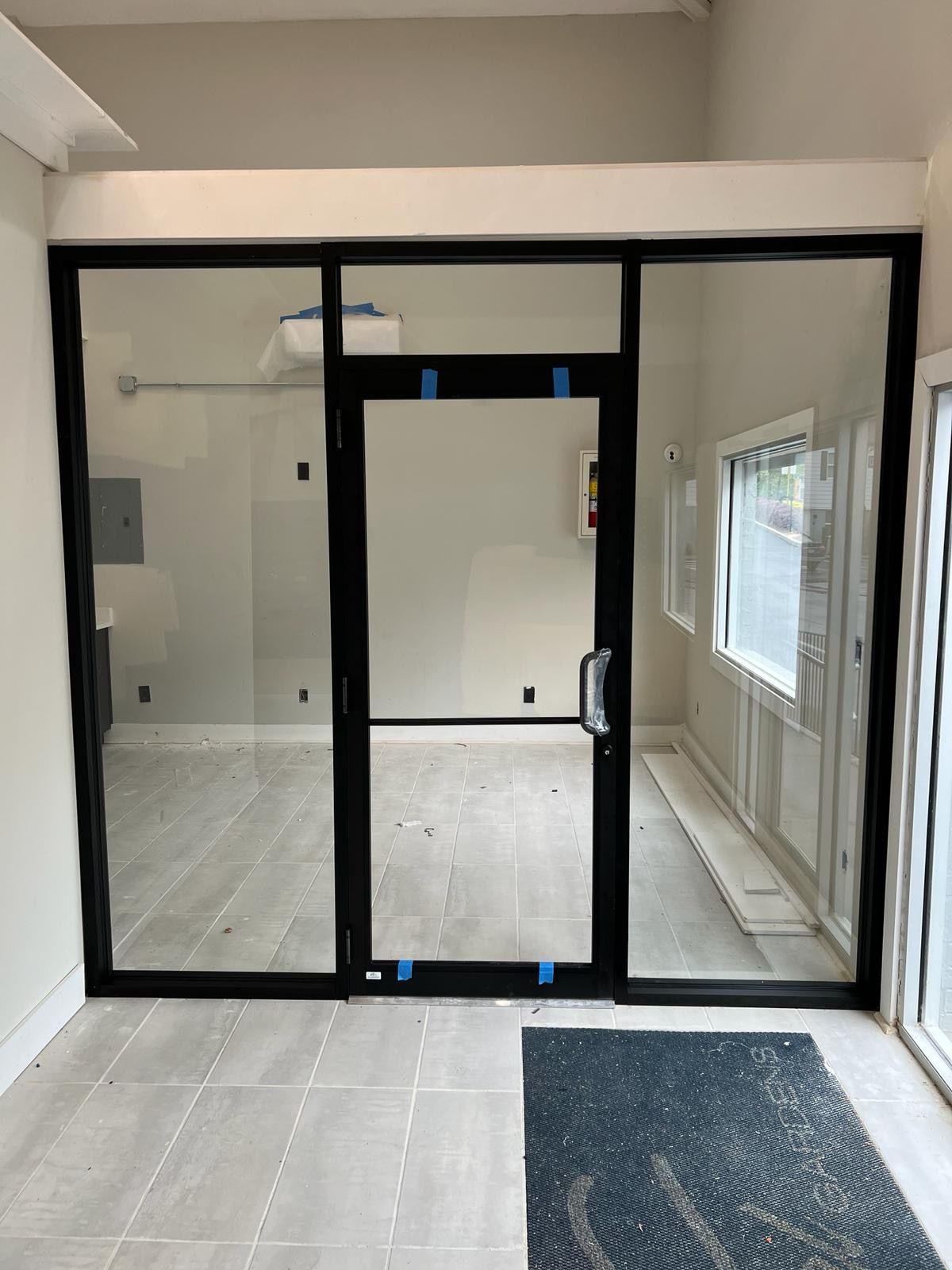 An empty room with a glass door and a rug.