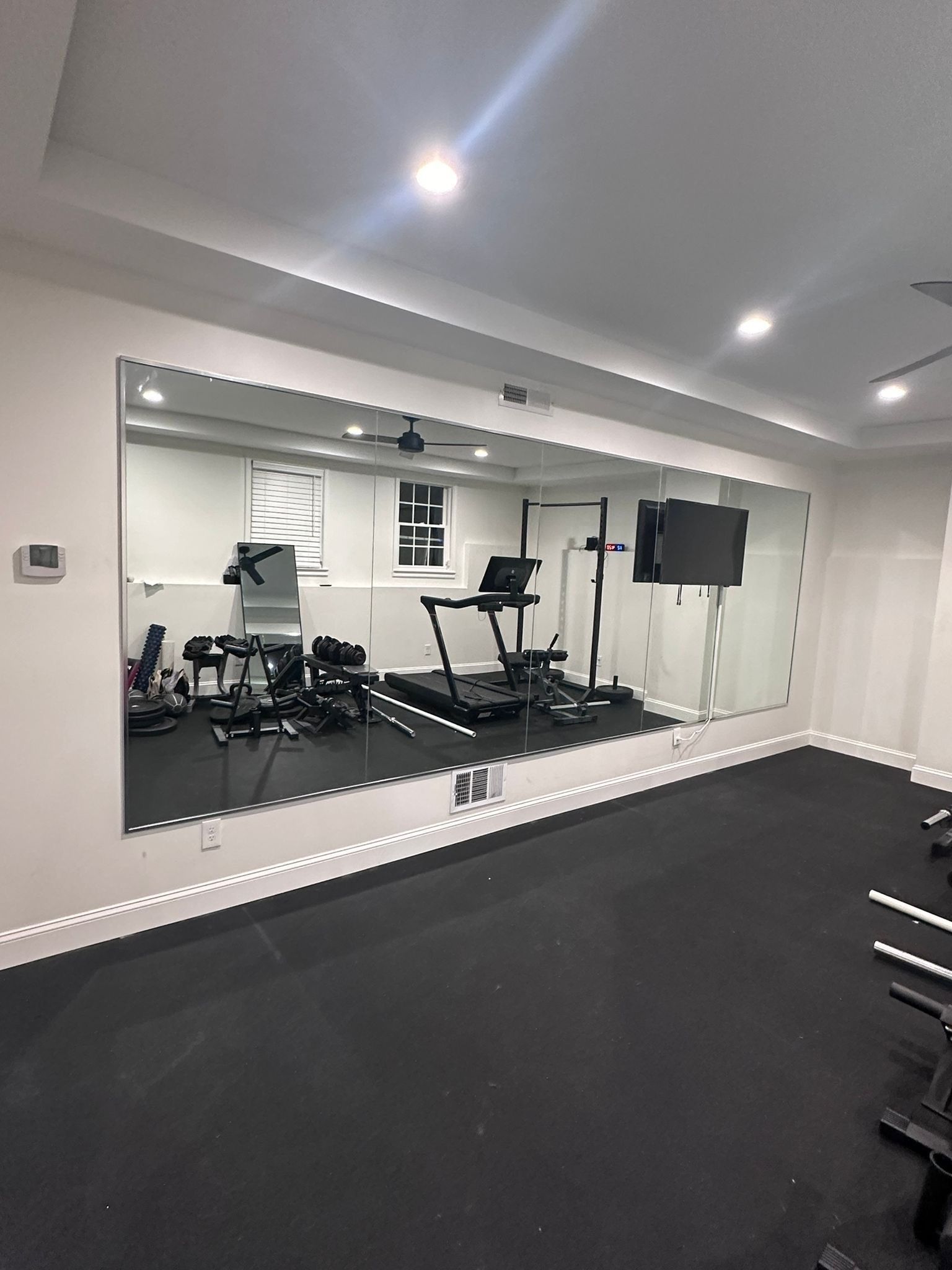 A gym with a treadmill and a large mirror on the wall.