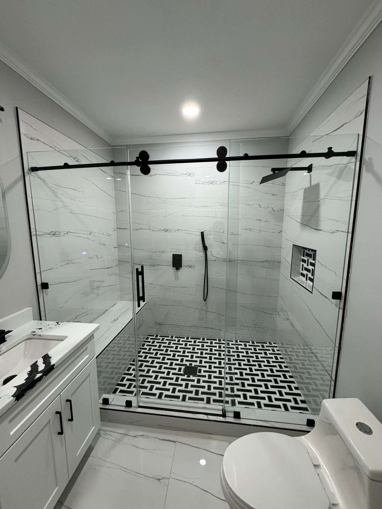 A bathroom with a walk in shower , sink , toilet and mirror.
