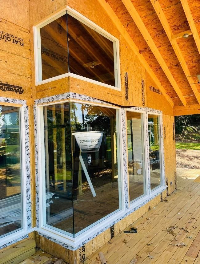 A house under construction with a lot of windows and a wooden deck.