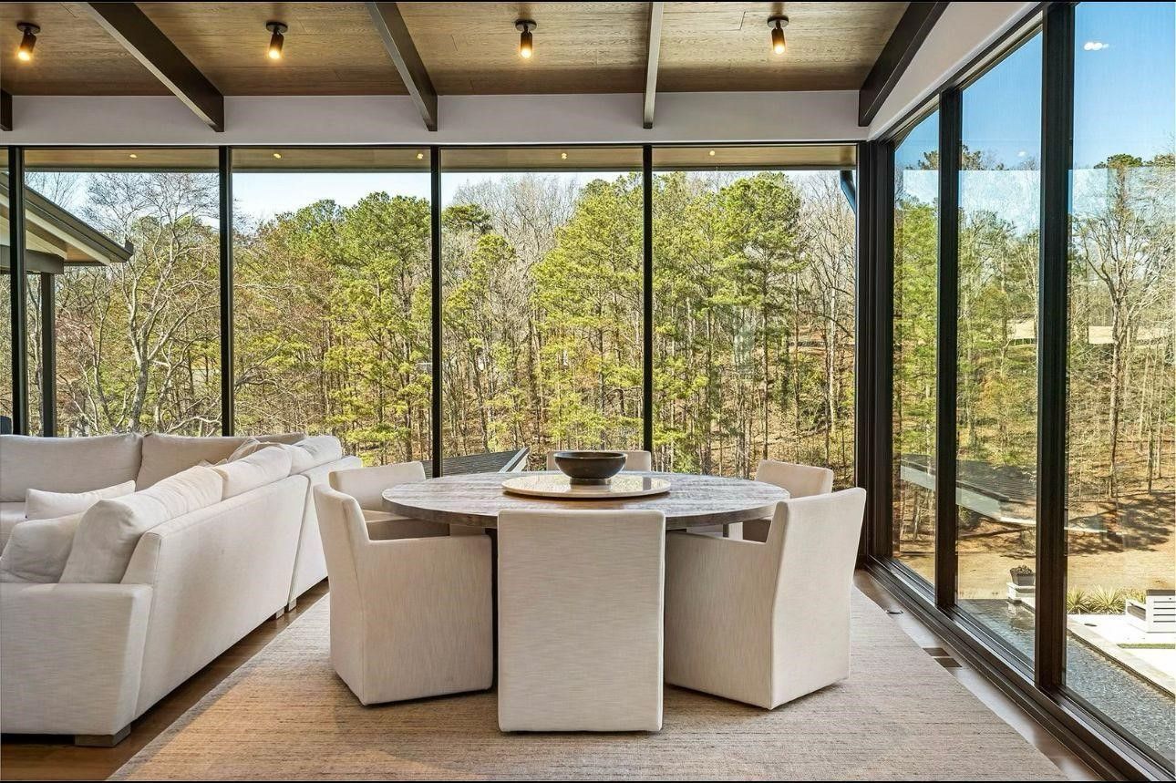 A living room with a table and chairs and a lot of windows.