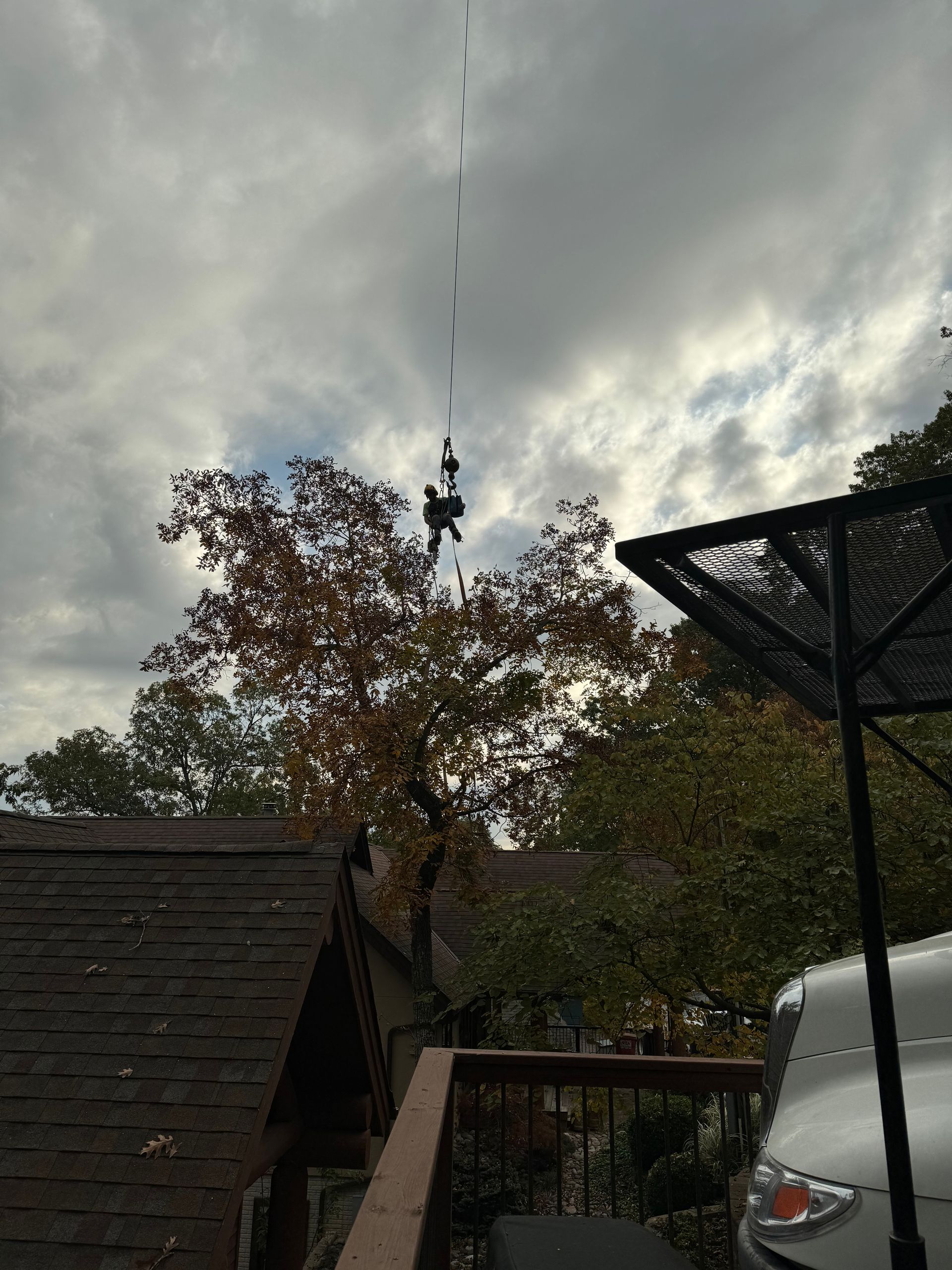 a white car is parked in front of a house with a cloudy sky in the background.