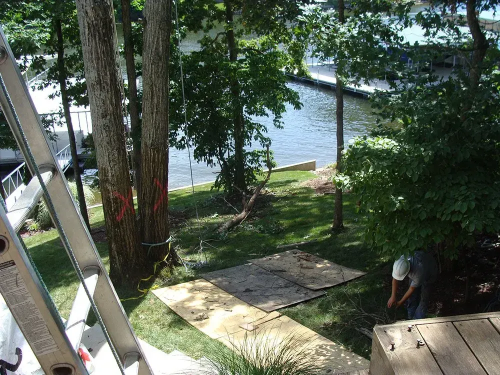 a man is working on a wooden deck next to a body of water