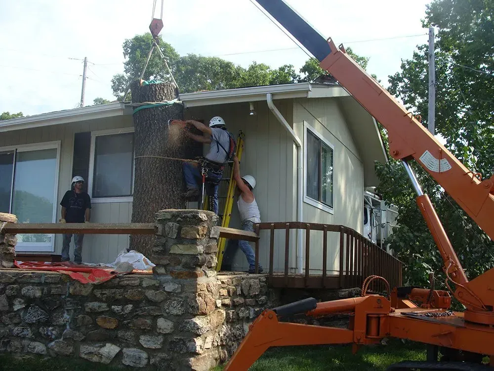 A crane is being used to remove a chimney from a house.