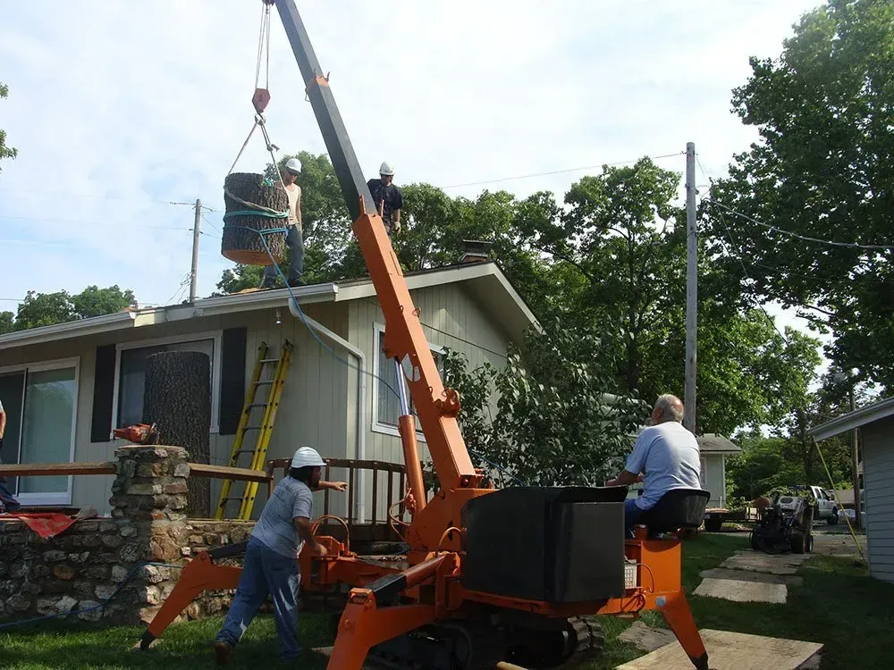 A crane is being used to lift a large object over a house.