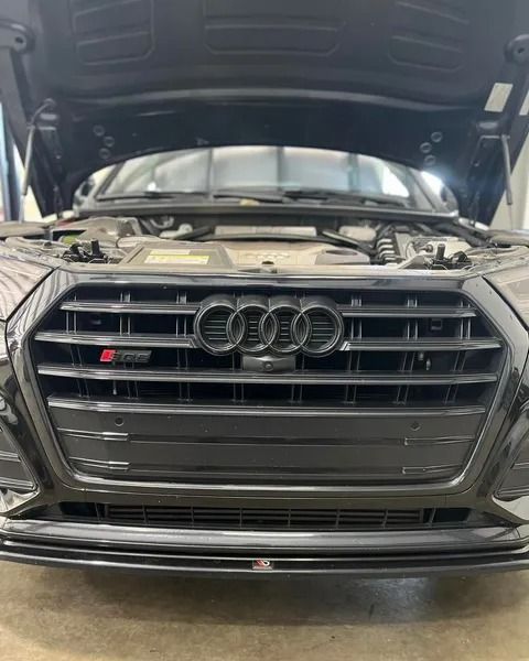 Black Audi S5 with hood open, showing front grille with the Audi rings emblem.