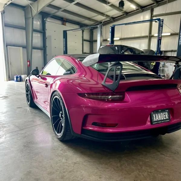 Pink Porsche 911 GT3 with a large spoiler in a garage.