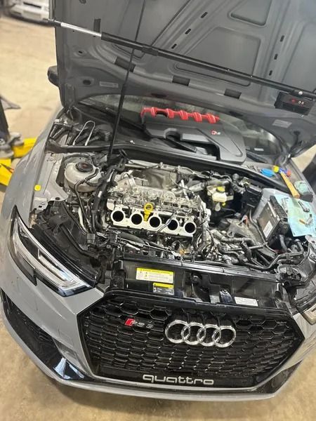 Gray Audi RS3 with open hood, engine bay exposed. Tools visible. Quattro badge on grill.